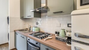 A compact kitchen with a gas stove, a toaster, and a refrigerator.