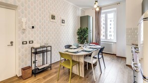 A modern kitchen with a dining area, featuring a wooden table, chairs, and a hanging light fixture.