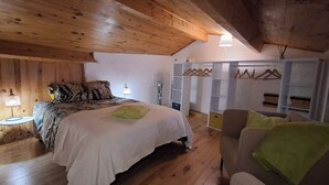 A wooden-paneled bedroom with a bed, bedside table, lamp, and a chair. - Small vacation home for 4 people. (Banne)