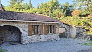 A stone building with a tiled roof, a small arched entrance, and wooden shutters. - Small vacation home for 4 people. (Banne)