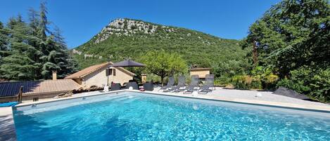 A pool with lounge chairs and a mountain backdrop.