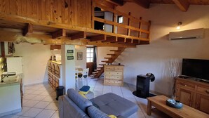 A spacious living area with a wooden staircase, a sofa, a TV, and a fireplace. - Small vacation home for 4 people. (Banne)
