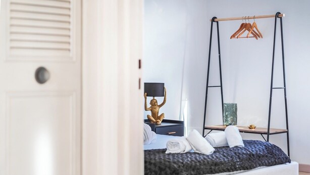 Ein Schlafzimmer mit einem Bett, einem Hängesessel, einem kleinen Tisch und einer dekorativen Buddha-Statue.