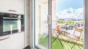 Eine moderne Küche mit einem De Dietrich-Ofen, einer Schiebetür zu einem Balkon mit Blick auf eine Stadtlandschaft und geparkte Autos.