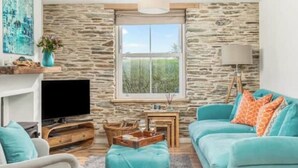 A living room with a stone wall, a television, a sofa, and a lamp.