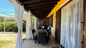 A covered patio area with a tiled floor, a table with chairs, and a wooden ceiling. - Terraced house with swimming pool, surrounded by nature, 250 meters from the sea (Marina, Tertenia)