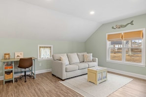 A room with a desk, chair, sofa, and a small table.