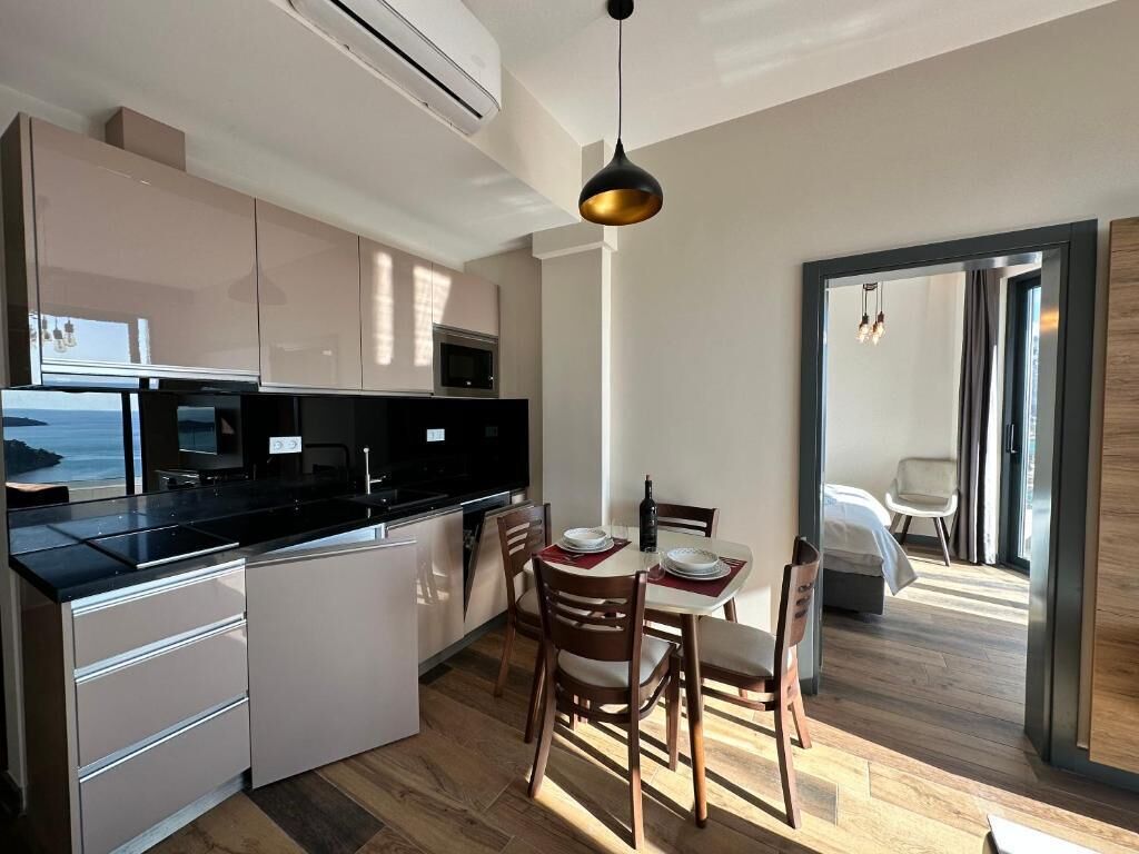 A modern kitchen with a dining area, featuring a large island, white cabinetry, and a view of the ocean.