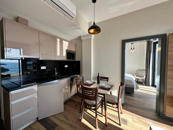 A modern kitchen with a dining area, featuring a large island, white cabinetry, and a view of the ocean. - Boreti Residence (Boreti)
