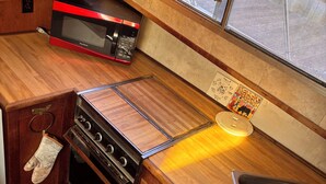 A compact kitchen with wooden cabinetry, a microwave, an oven, and a sink.