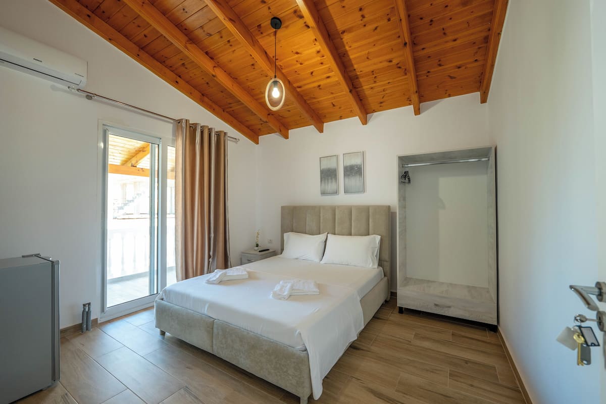 A bedroom with a bed, a wardrobe, a bedside table, and a window with curtains.