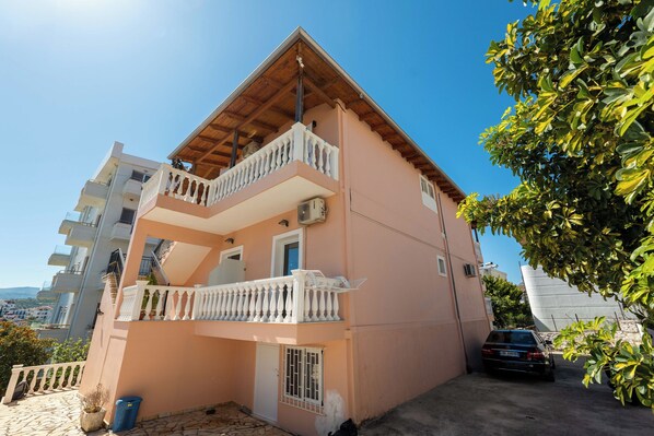 A multi-story building with balconies, a car parked in front, and a clear sky. - Sunny Villa (Ksamil)