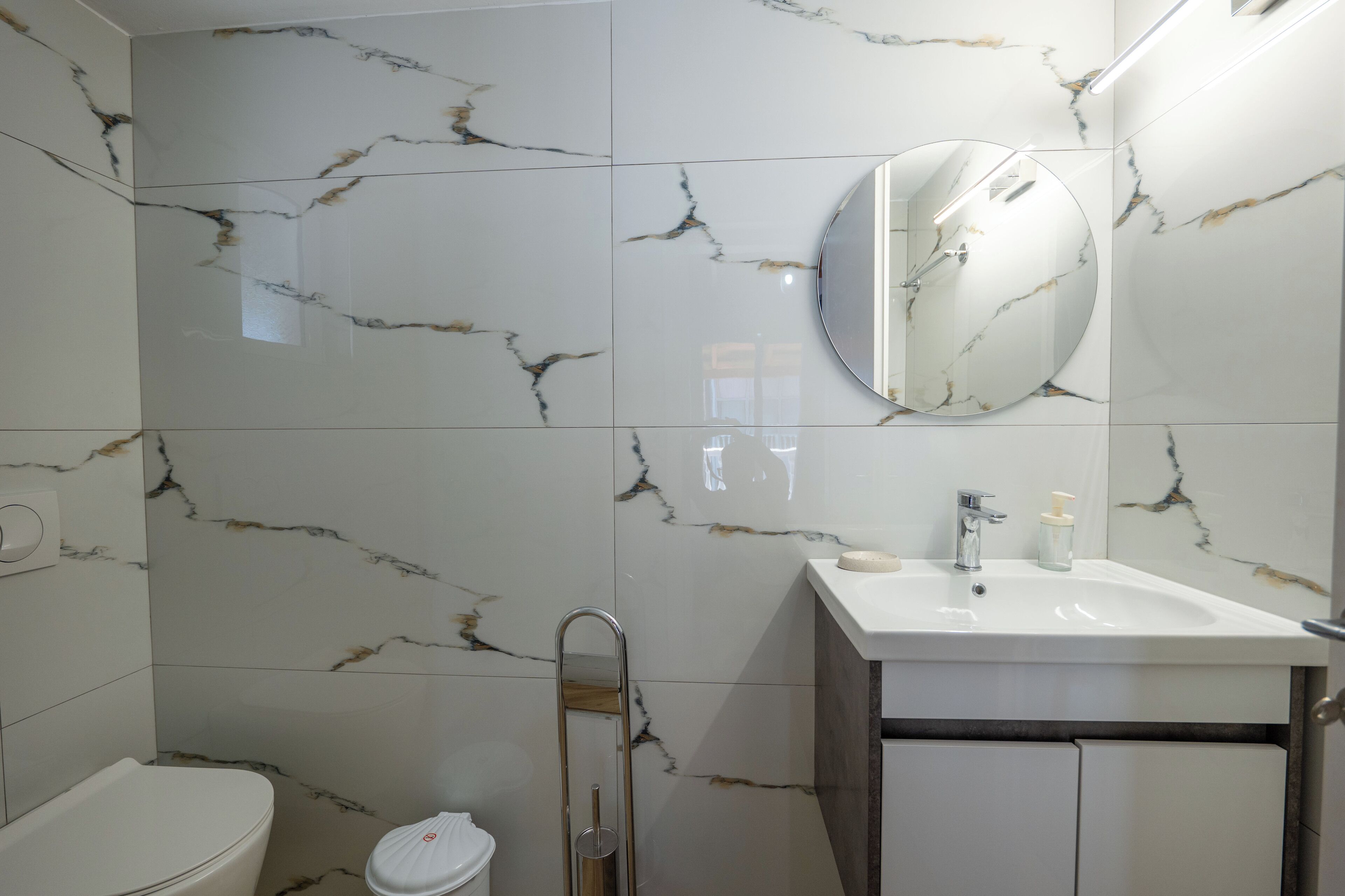 Une salle de bain avec un lavabo blanc, un miroir et des toilettes.
