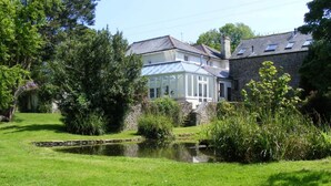 A house with a pond, surrounded by lush greenery and trees.
