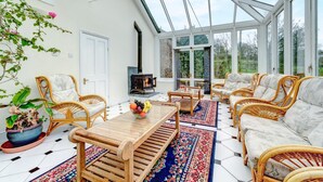 A conservatory with wicker furniture, a fireplace, and a large window.