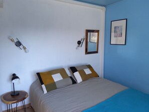 A bedroom with a bed, a round wooden side table, a desk lamp, a wall clock, a mirror, and a framed picture. - Friendly MAS with swimming pool and large garden in Saint Rémy de Provence (Saint-Rémy-de-Provence)
