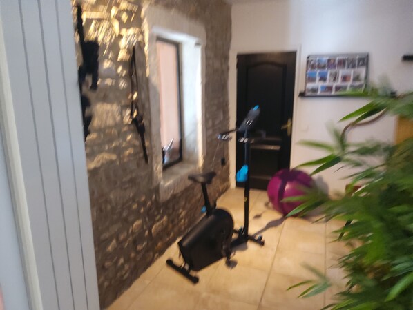 A room with a stone wall, a window, a door, and exercise equipment. - Friendly MAS with swimming pool and large garden in Saint Rémy de Provence (Saint-Rémy-de-Provence)