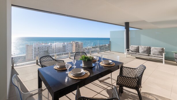 A balcony with a dining table set for four, overlooking a cityscape and the sea. - Bego a Sea View in Fuengirola (Fuengirola)