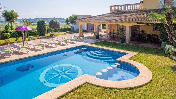 A swimming pool with a sun dial design, surrounded by lounge chairs and a covered patio area. - Casa Judith in Mallorca (Muro)