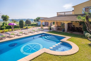 A swimming pool with a sun dial design, surrounded by lounge chairs and a covered patio area. - Casa Judith in Mallorca (Muro)