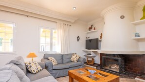 A living room with a sofa, a wooden coffee table, a fireplace, and a television. - Casa Judith in Mallorca (Muro)
