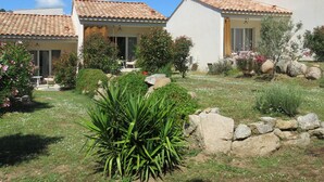A residential property with a tiled roof, a patio with outdoor furniture, and a garden with rocks and plants. - Les Terrasses d'Arutoli (Porto-Vecchio)