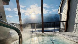 A clear view of a swimming pool with a lifeguard stand, a metal railing, and a mountain backdrop.