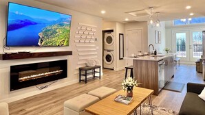 A modern living room with a flat-screen TV, fireplace, and seating area.