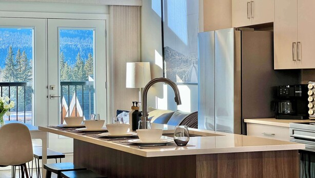 A modern kitchen with a central island, stainless steel appliances, and a view of the outdoors.