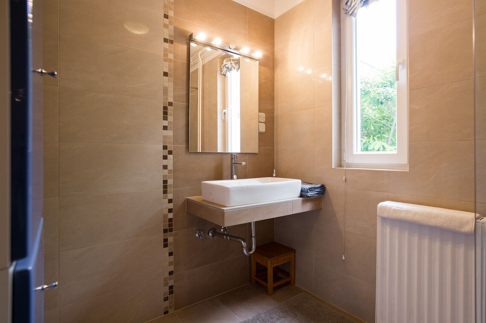 Un bany amb un lavabo blanc, un mirall i una finestra.