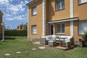 A two-story building with a patio area featuring wicker furniture and a stone wall.
