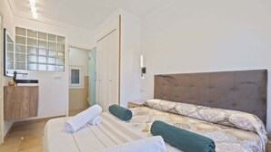 Een hotelkamer met een bed, een badkamer, een spiegel en een klein kastje.