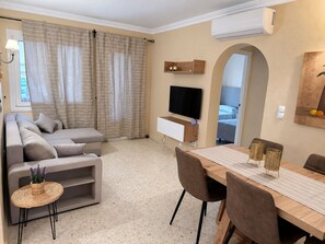 A modern living room with a sofa, TV, dining table, and chairs.
