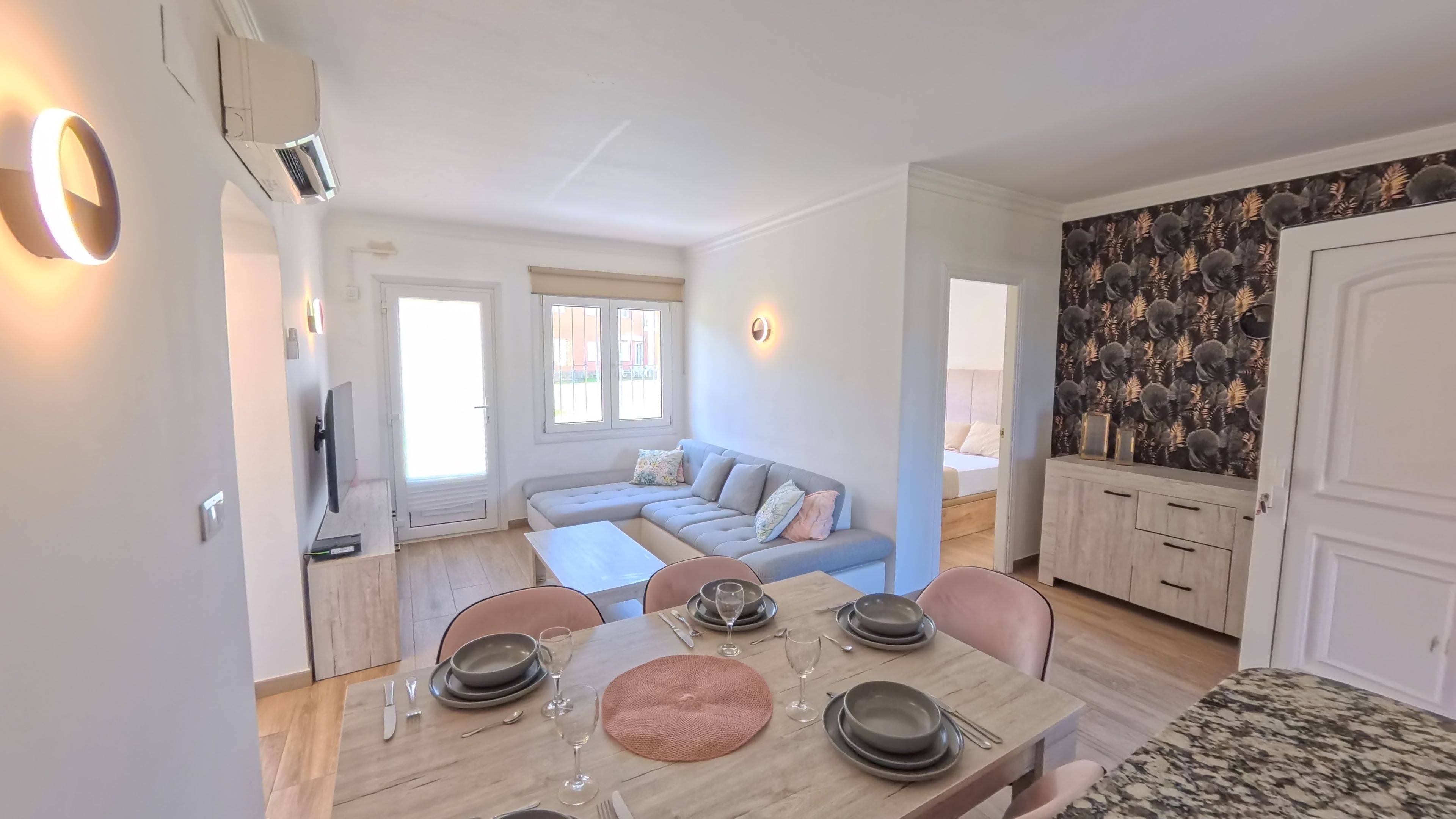 A modern living space with a dining area, a sofa, a kitchen, and a decorative wall.