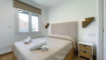 Une chambre à coucher comprenant un lit, une fenêtre, une table de chevet et un luminaire fixé au mur.