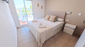 A hotel room with a bed, a nightstand, a wall-mounted light, and a view of the outdoors. - Villa Velissia by Midelisa. (Oliva)