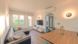 Ein modernes Wohnzimmer mit einer Couch, einem Fernseher und einem Essbereich.