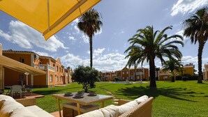 Un patio con mobiliario exterior, palmeras y una piscina.