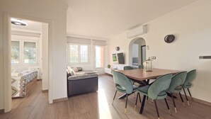 Una sala de estar moderna con un sofá, una mesa de comedor con sillas y un televisor montado en la pared.