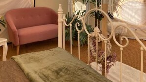 A room with a bed, a pink sofa, and a white metal bed frame. - Flower Farm Glamping Retreat in Suffolk (Ipswich)