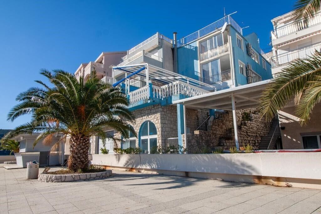 A multi-story building with a blue and white facade, stone accents, and a palm tree in the foreground. - 2 Triple Room With Private Parking (Neum)