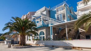 A multi-story building with a blue and white facade, stone accents, and a palm tree in the foreground. - 5 Double room with Private Parking (Neum)