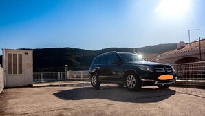 A black SUV parked on a concrete surface with a mountainous backdrop and a clear sky. - 6 Double room with Private Parking (Neum)