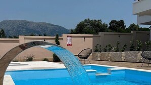 A swimming pool with a water feature, surrounded by a low wall and a chair. - NEW! Apartment 4 with Pool in Bar, Montenegro (Bar)