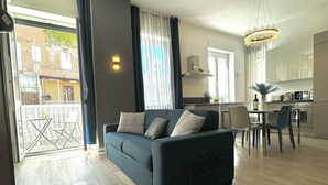 Ett modernt vardagsrum med soffa, matplats och kök.