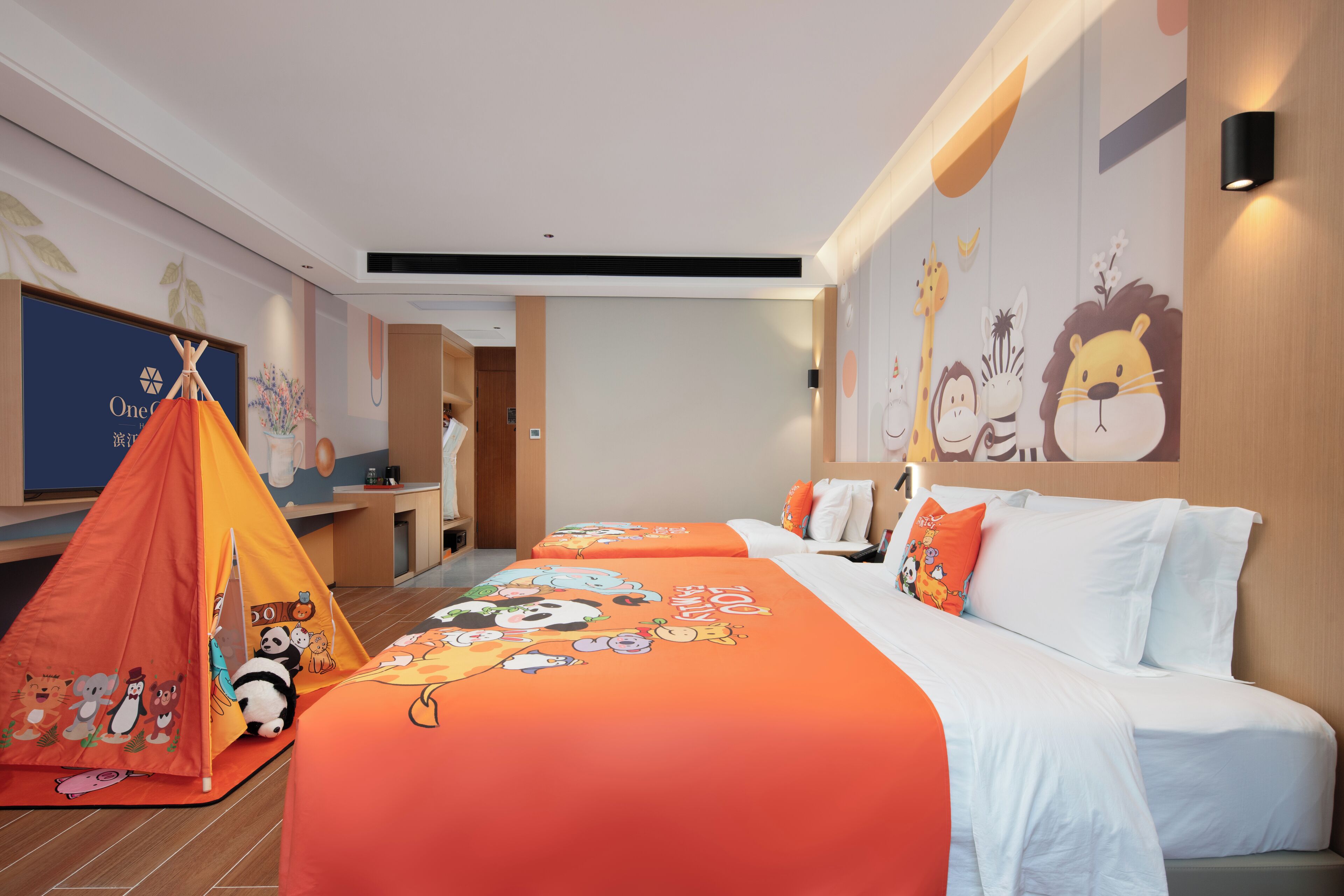 A hotel room with two beds, a play tent, and cartoon-themed bedding.