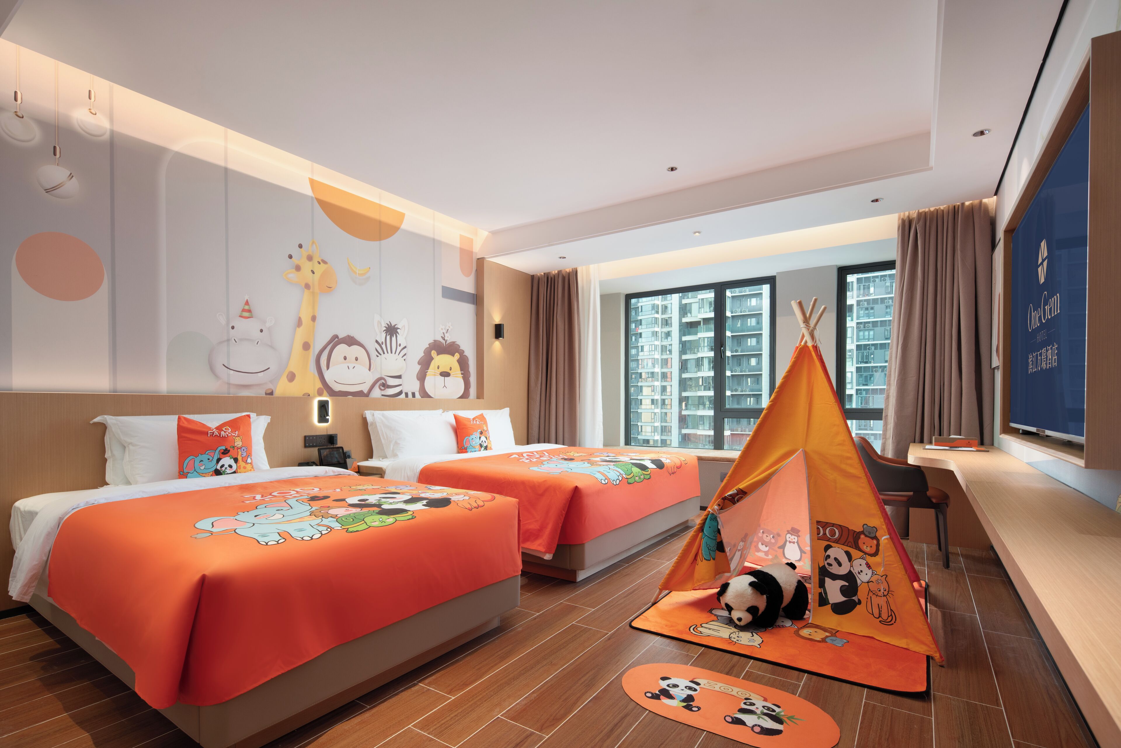 Una habitación de hotel con dos camas, un ventanal grande, una carpa de juegos y decoración con motivos de dibujos animados.