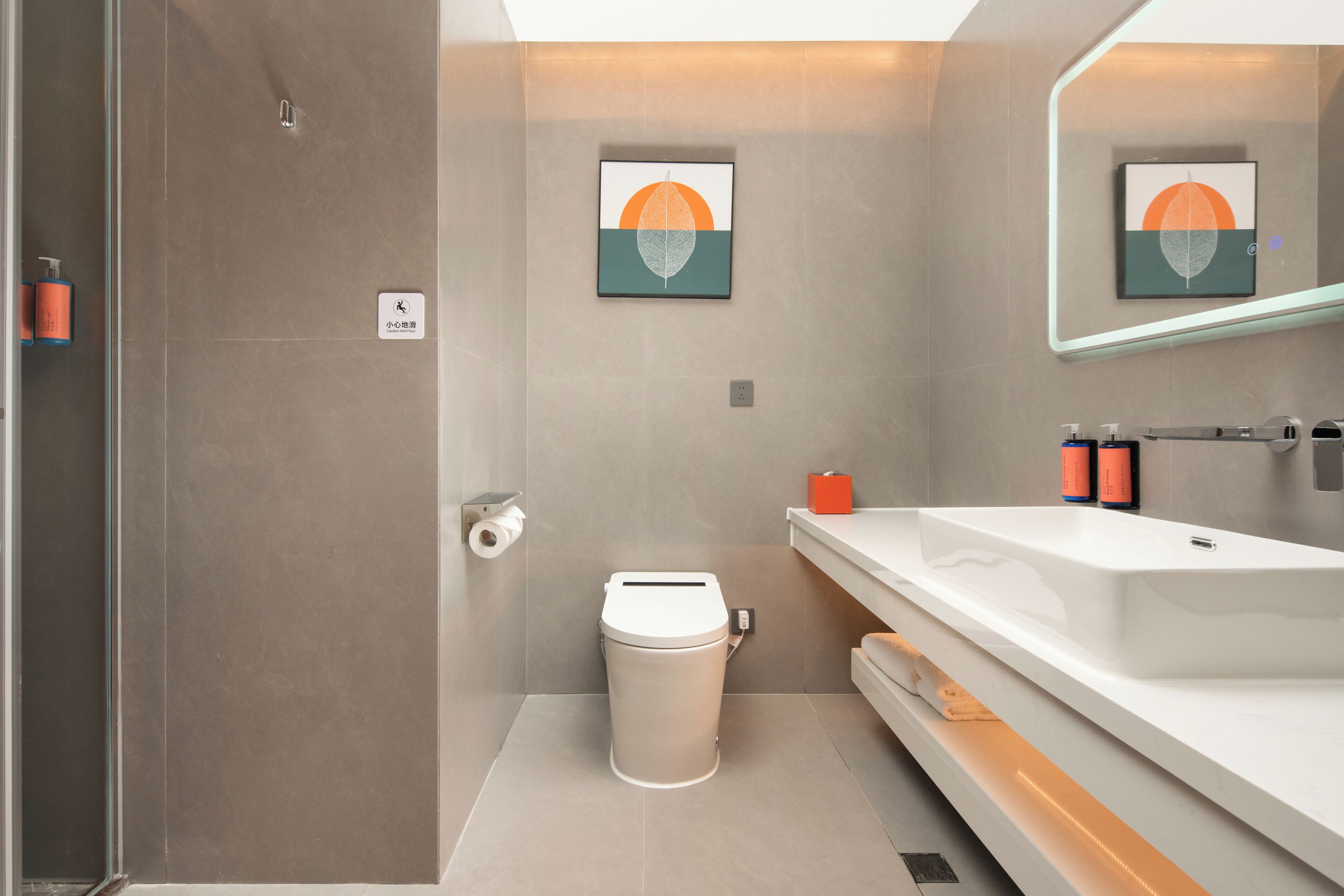 Ein modernes Badezimmer mit Toilette, Waschbecken und Spiegel. An der Wand hängen zwei gerahmte Kunstwerke.