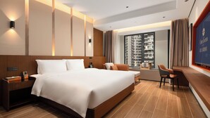 Quarto de hotel moderno com uma cama grande, uma escrivaninha e vista para um edifício alto.