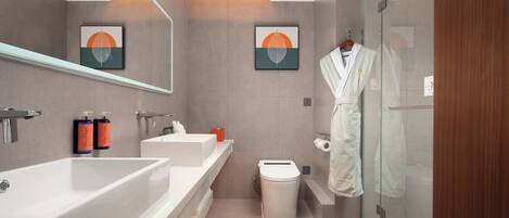 A modern bathroom with a large bathtub, a toilet, and a glass shower enclosure.